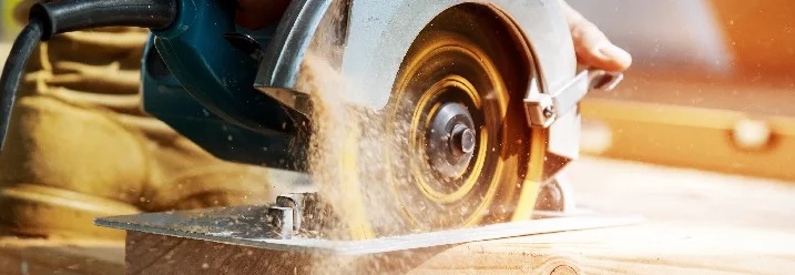 Hand schneidet Holz mit Kreissäge